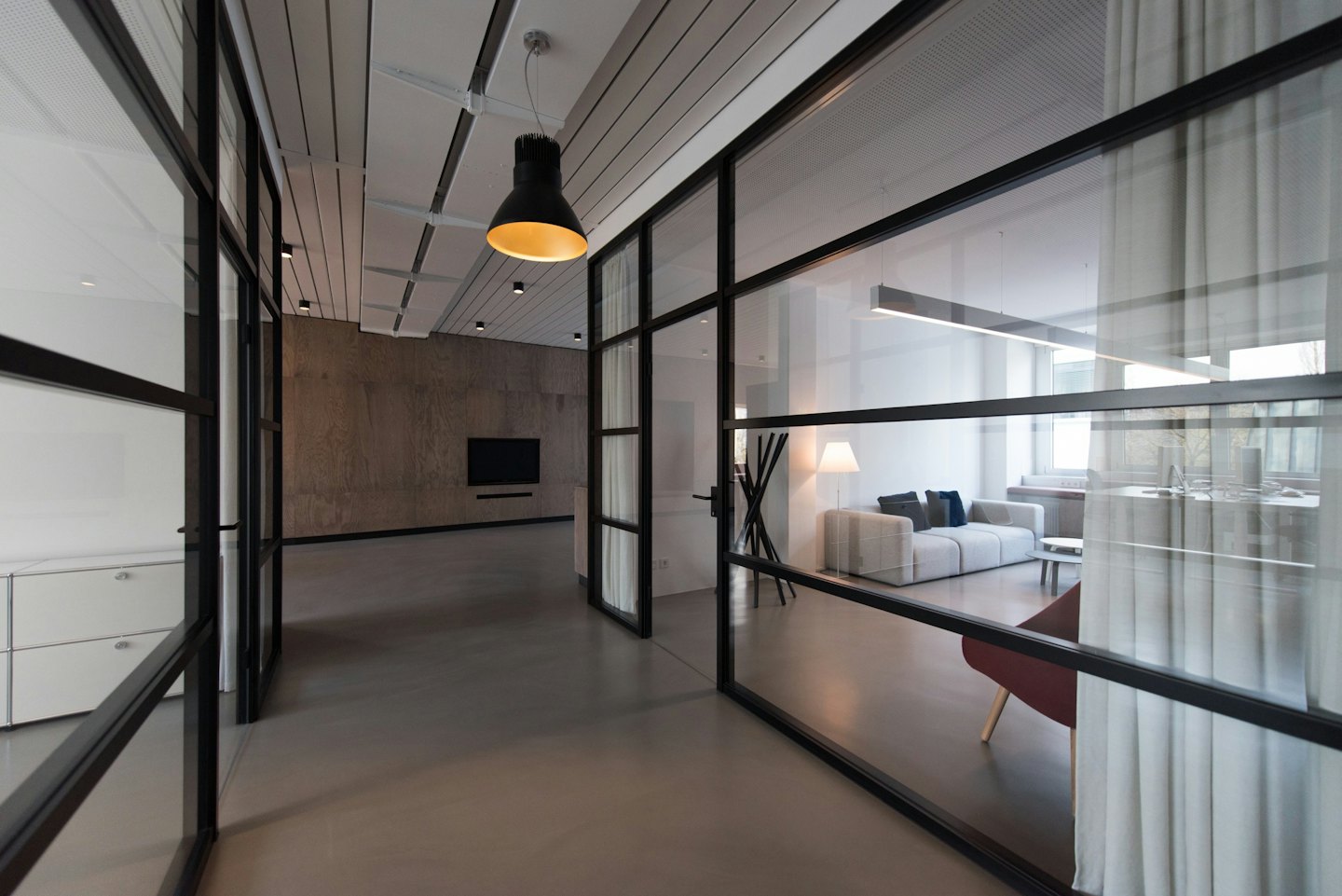 Sleek office corridor with glass partitions and modern furniture.